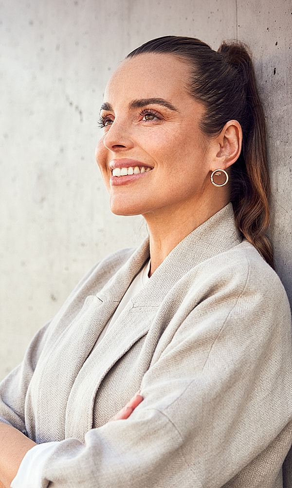 Smiling woman in a stylish outfit, side profile.