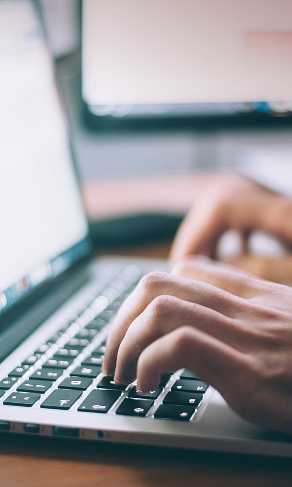 Hands typing on a laptop keyboard.