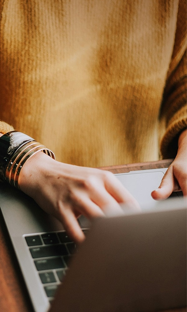 Person typing on laptop with stylish bracelets.