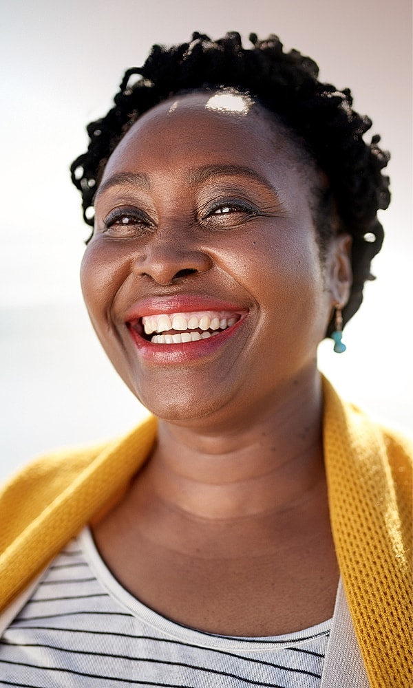 Smiling woman with natural hair and yellow sweater.