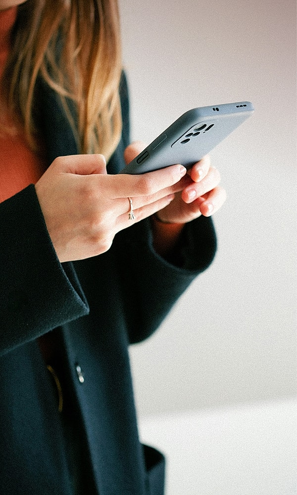 Person holding smartphone with casual outfit.