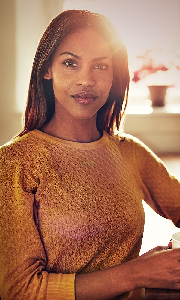 Woman in yellow sweater sitting by window.