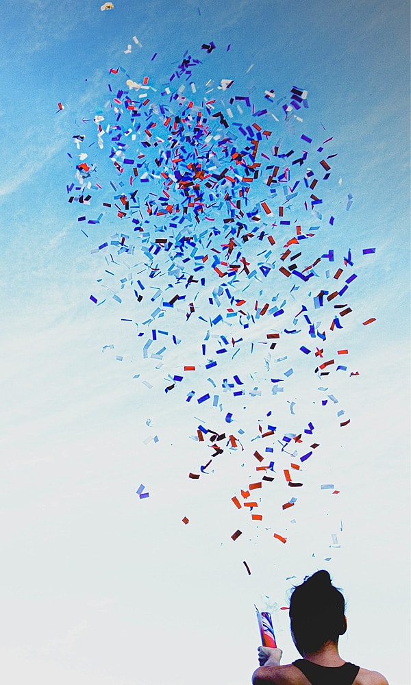 Person releasing colorful confetti into the sky.