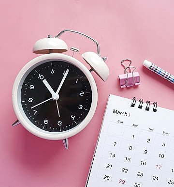 Alarm clock and calendar on pink background