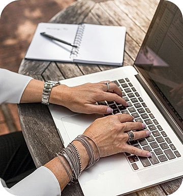 Person typing on laptop, notebook beside them.