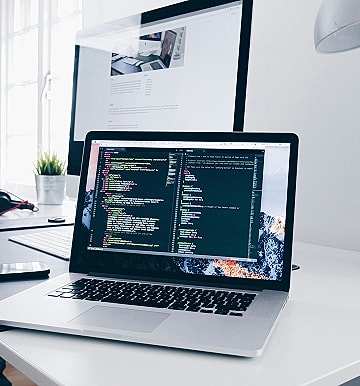 Laptop displaying code on a modern desk.