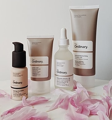 The Ordinary skincare products with flower petals.