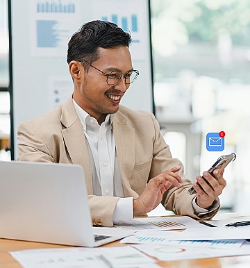 Businessman checking phone notifications at desk.